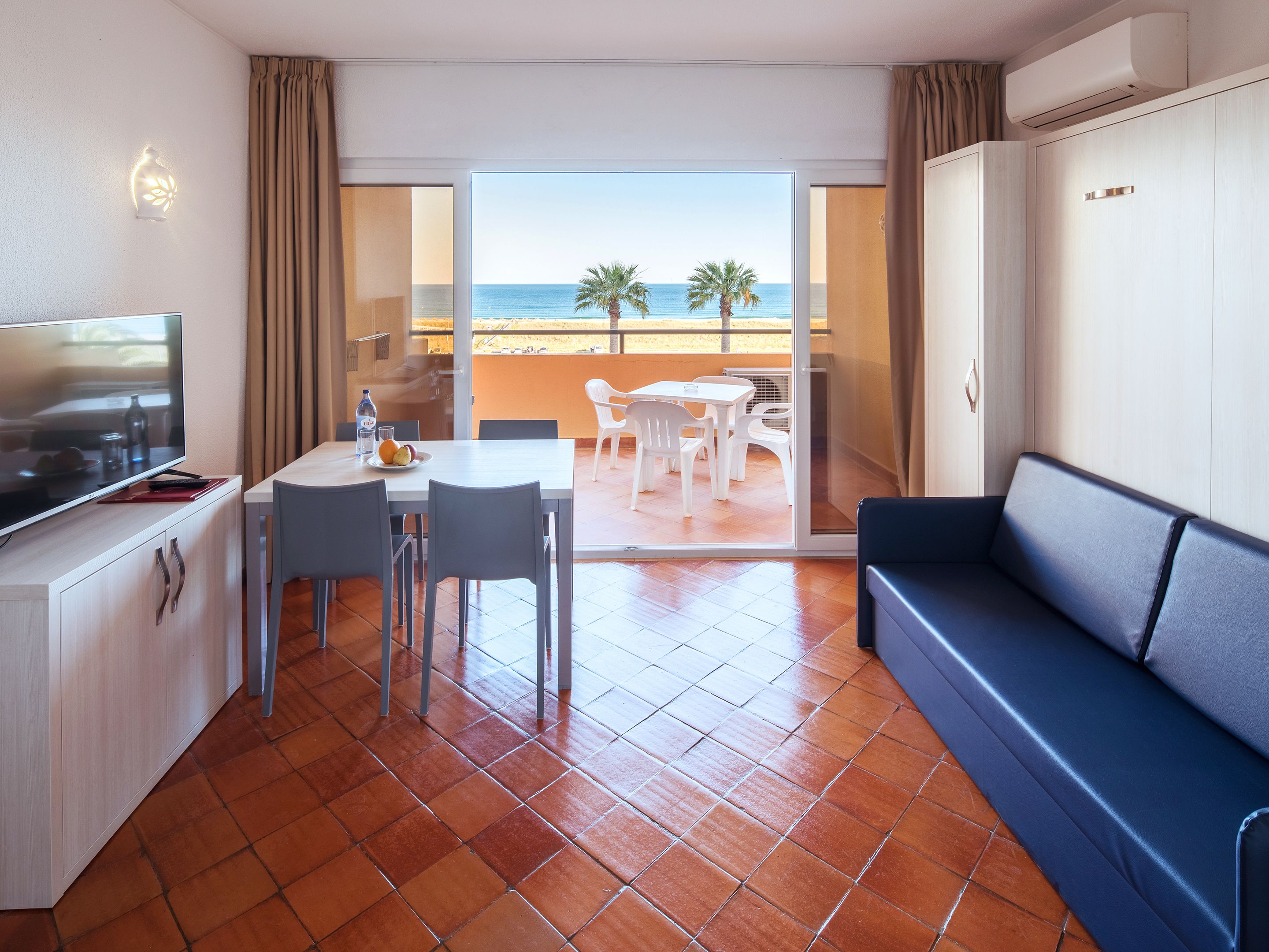 Een hotelkamer met balkon, een eethoek en een zithoek.