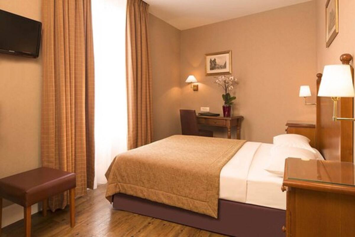 Une chambre d’hôtel avec un lit, un bureau, une chaise, une télévision et une lampe.