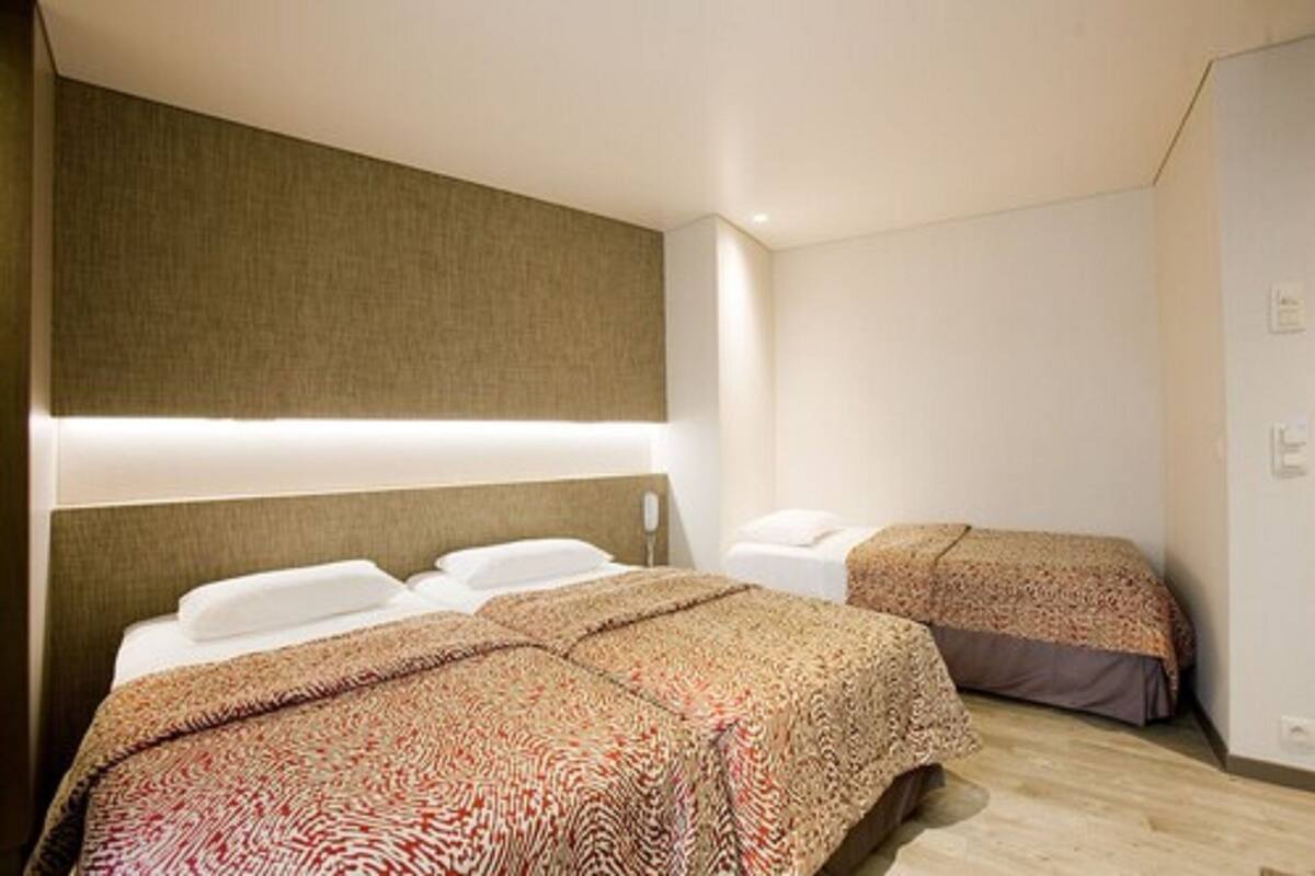 Une chambre d’hôtel avec deux lits, chacun doté d’une literie à motifs, d’une tête de lit et d’un luminaire fixé au mur.