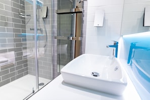 Features a sleek sink and glass-enclosed shower area with clean lines and minimalist design.
