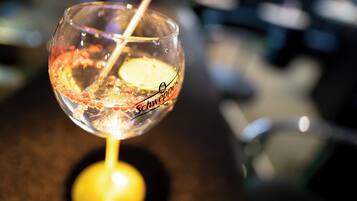 A clear glass with a straw, possibly containing a beverage, on a surface with a blurred background.