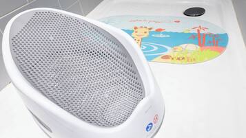 A white portable heater with a perforated basket and a children's bath mat with a giraffe design.