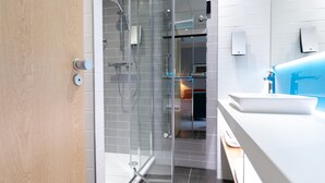 A modern bathroom with a glass shower enclosure, a white sink, and a visible towel rack.