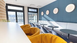 A modern interior with yellow seating, a white counter, and a blue wall with circular light fixtures.