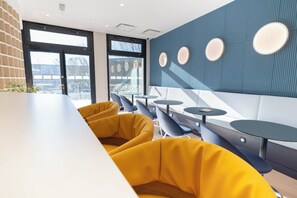 A modern interior with yellow seating, a white counter, and a blue wall with circular light fixtures.