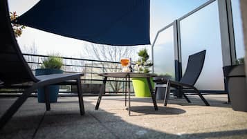 A patio with two chairs, a table, and a bottle of wine.