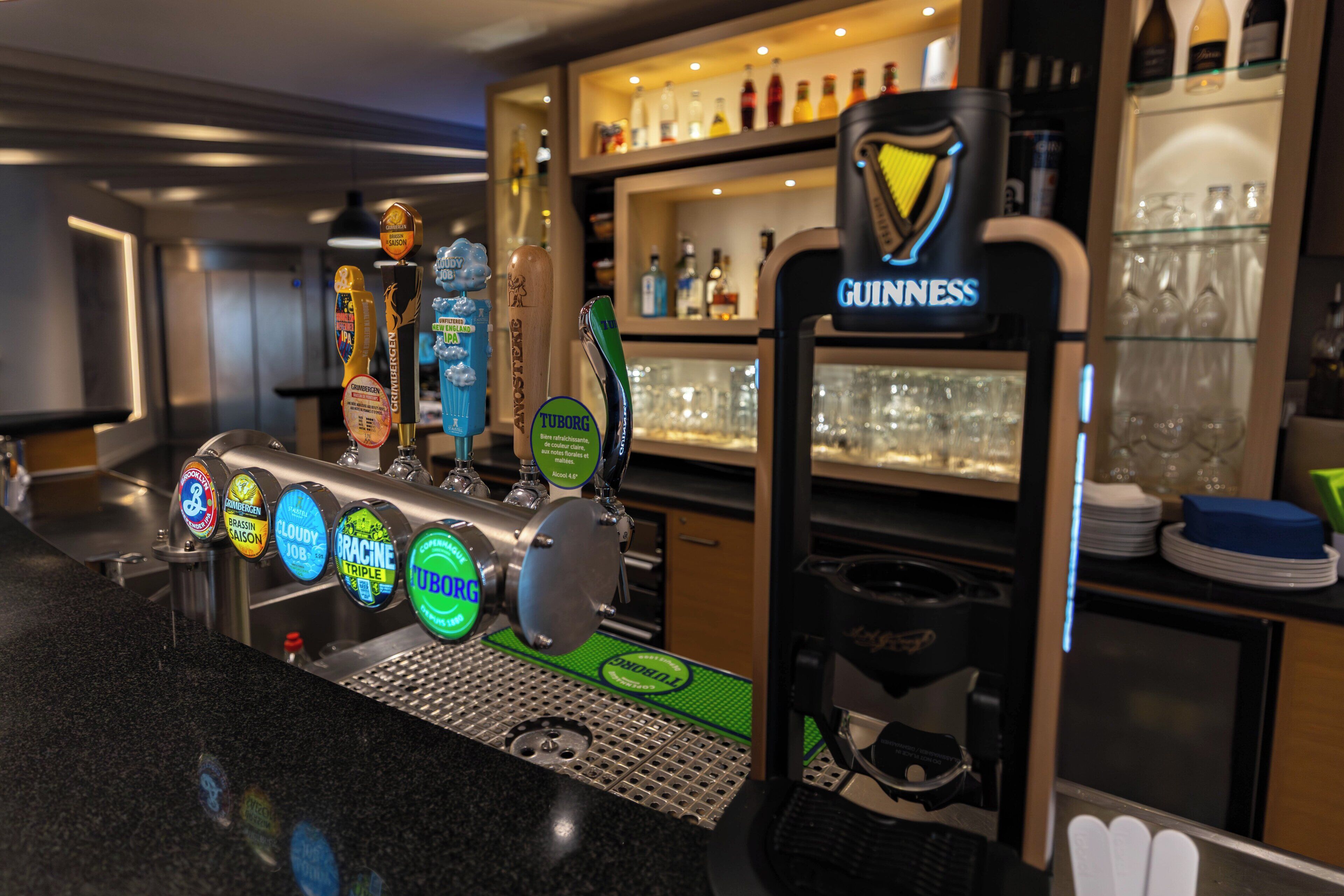 En bardisk med ett område för ölkranar, en Guinness-kran och ett urval av ölflaskor på hyllor.