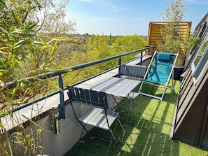 Enjoy the serene views of lush green surroundings from this balcony with a pool and comfortable seating.