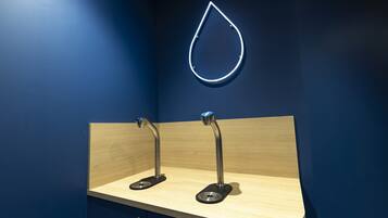 Un baño moderno con una pared azul oscuro, un mueble de tocador de madera y dos grifos metálicos.