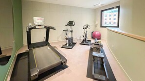 A gym with treadmills, stationary bikes, and a large exercise ball.