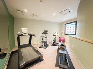 A gym with treadmills, stationary bikes, and a large exercise ball.