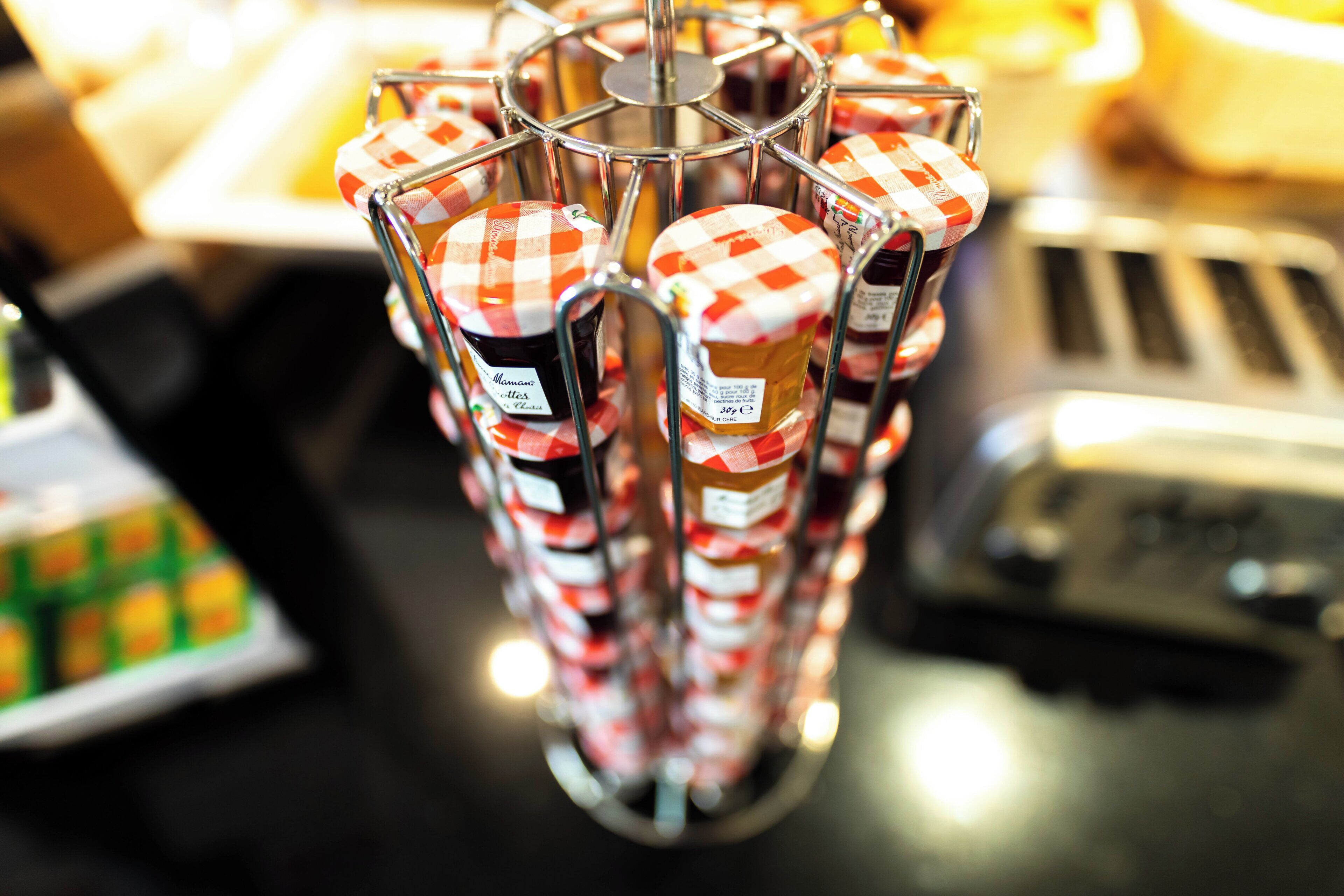 A display of jars with checkered lids, possibly containing jam or preserves, arranged on a metal rack.