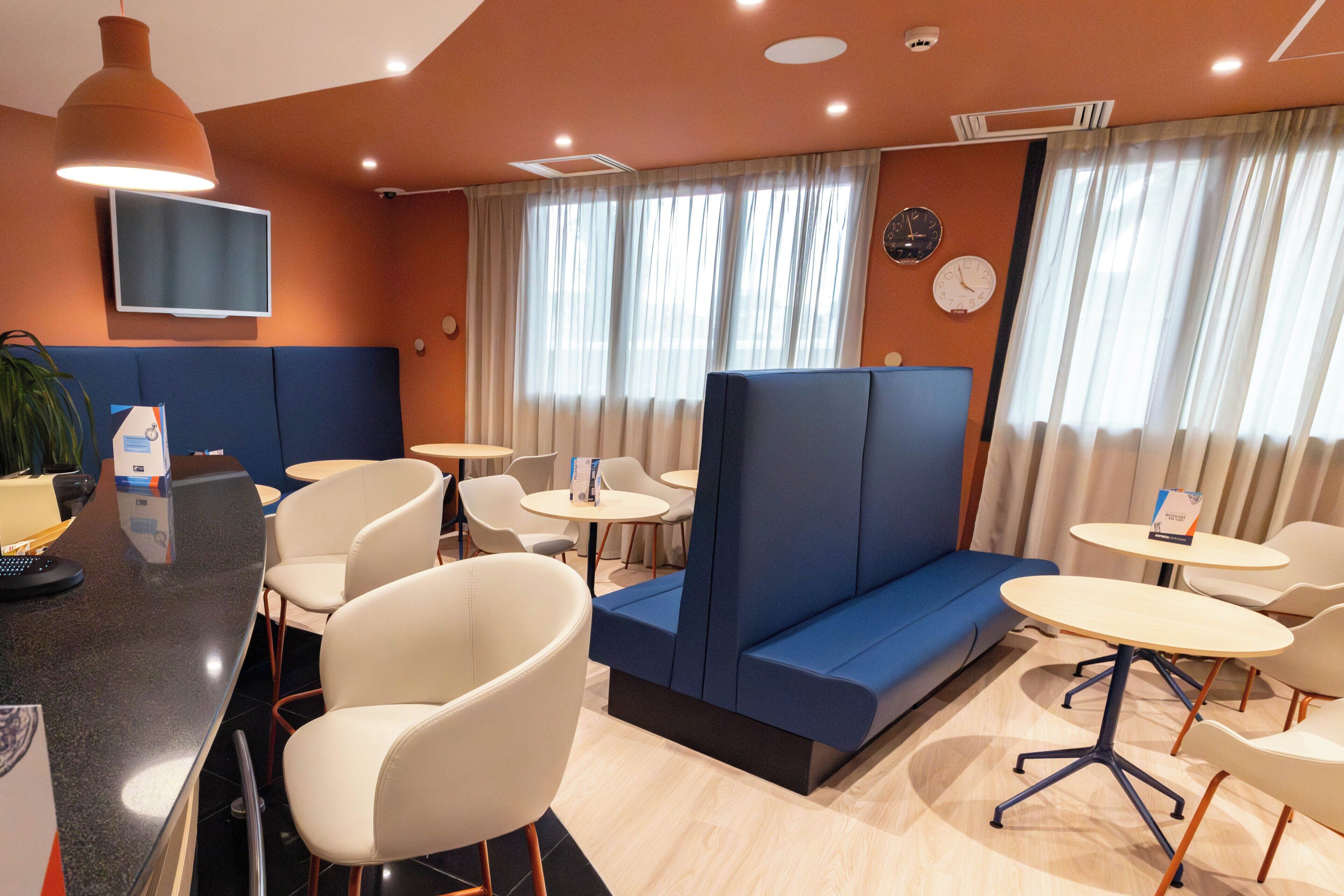 A hotel lobby with seating areas, a reception desk, and a television mounted on the wall.