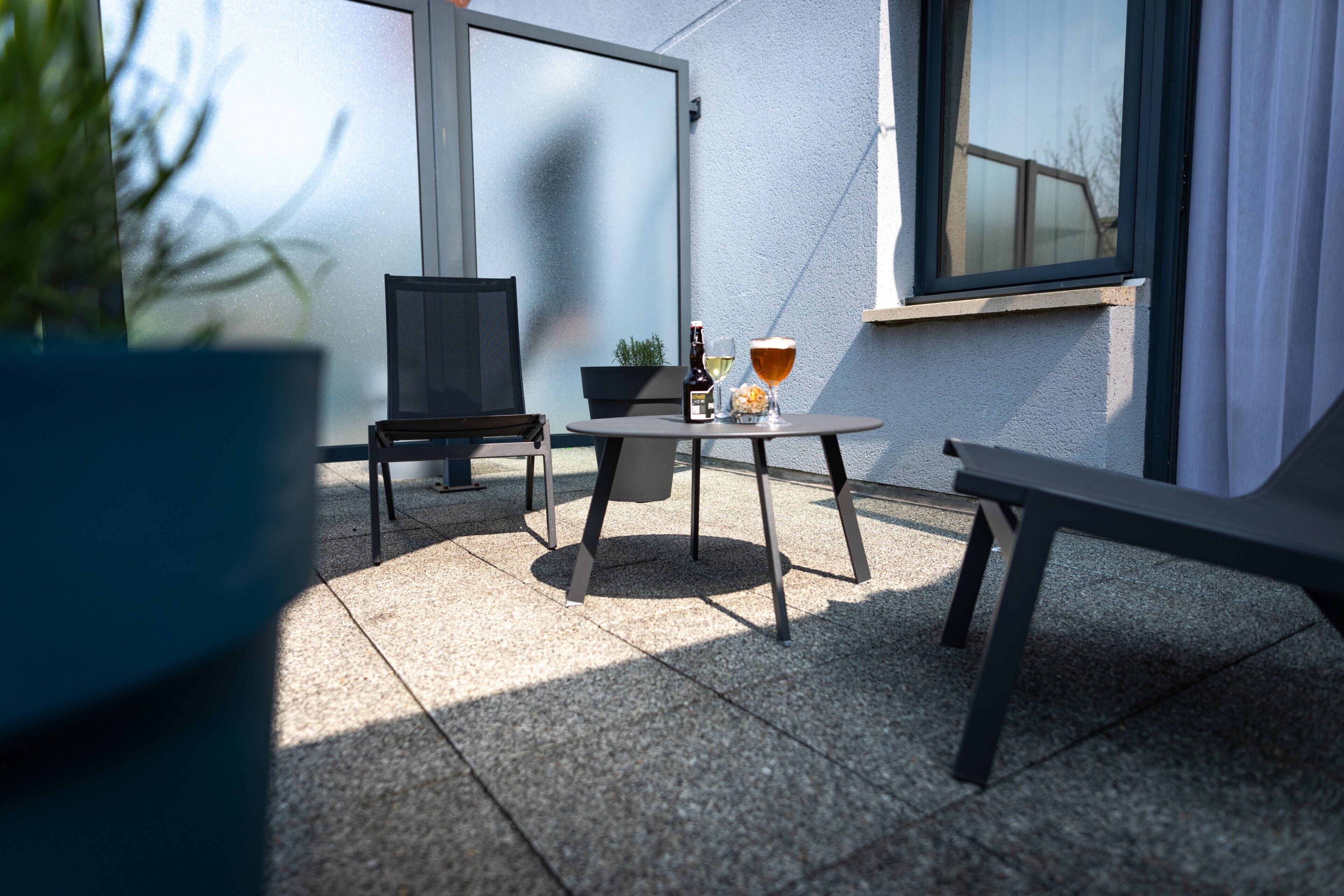 A patio with a table, chairs, a bottle, and a glass.