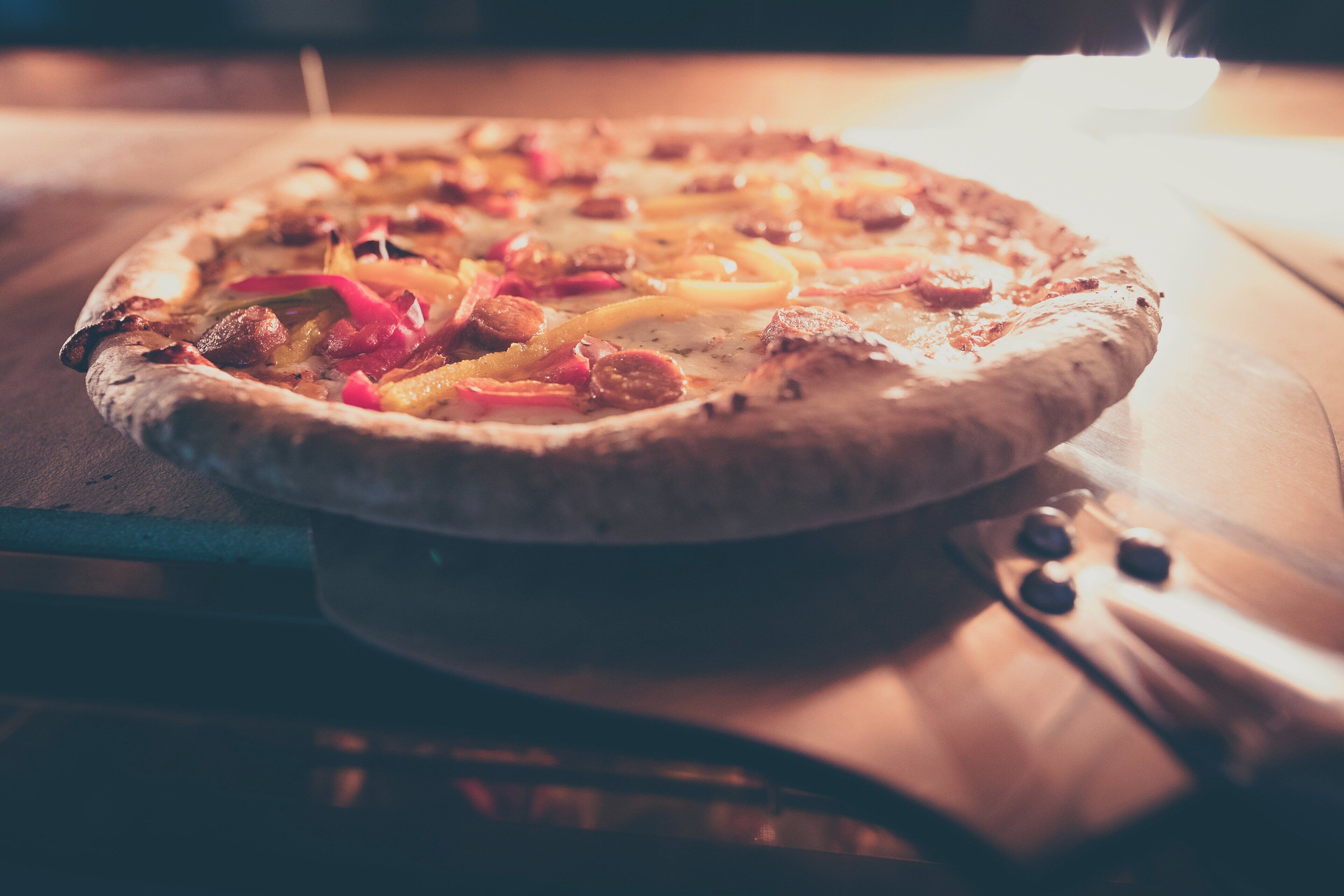 A pizza on a wooden board inside an oven.