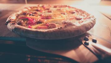 A pizza on a wooden board inside an oven.