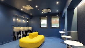A modern lounge area with a yellow sofa, white chairs, and small tables.
