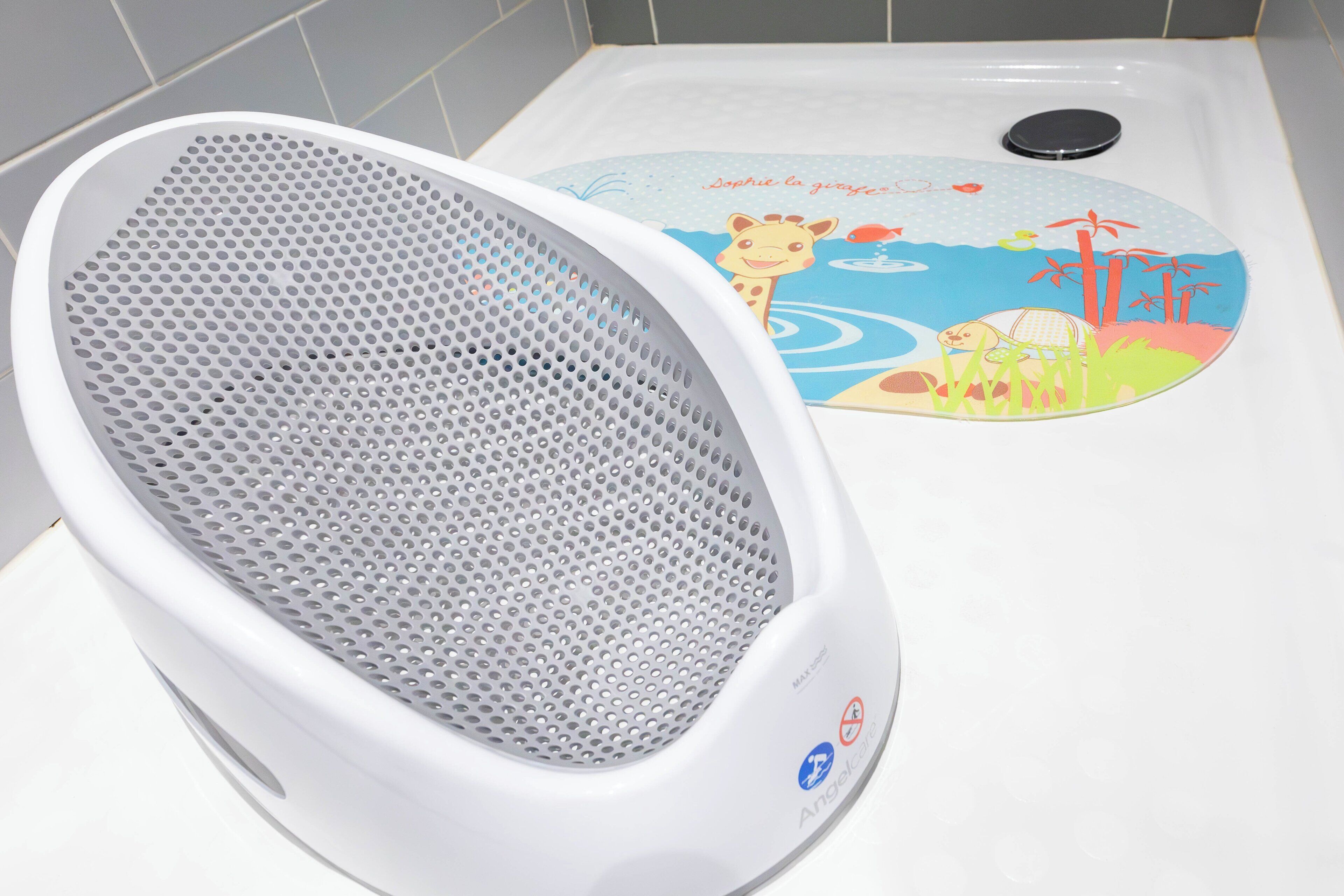A white portable heater with a perforated metal front, a children's mat with animal illustrations, and a black circular object on the floor.