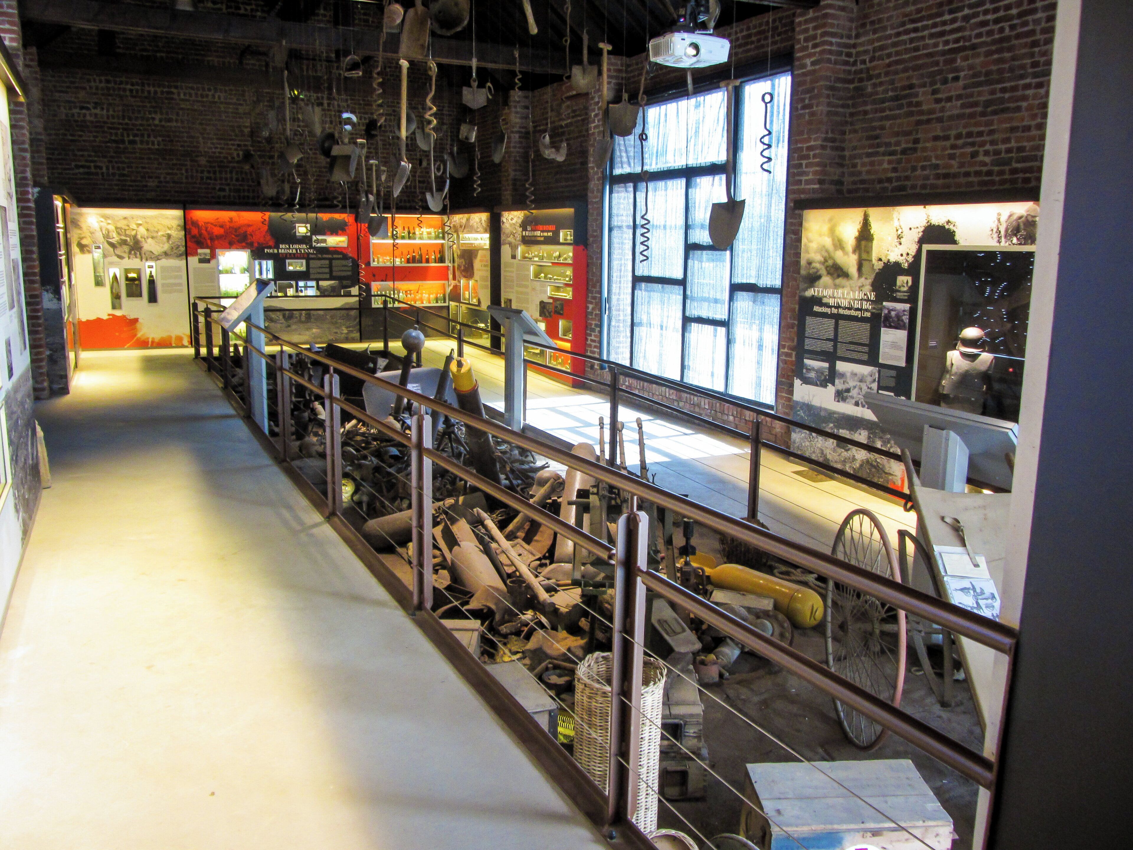 An industrial-style exhibition space with metal railings, historical artifacts, and informational displays.