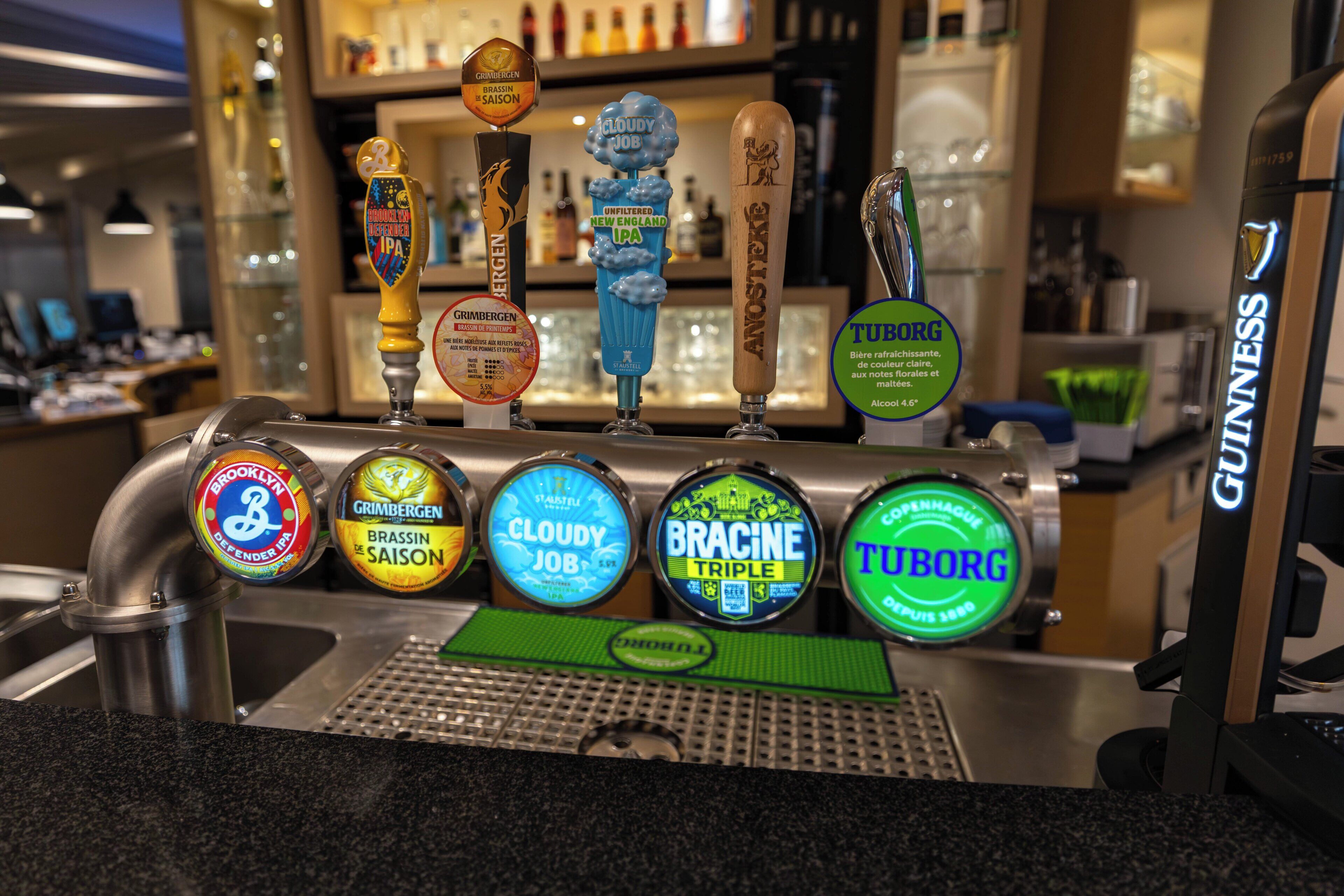 A bar with multiple beer taps, including brands like Brooklyn, Grimbergen, and Tuborg.