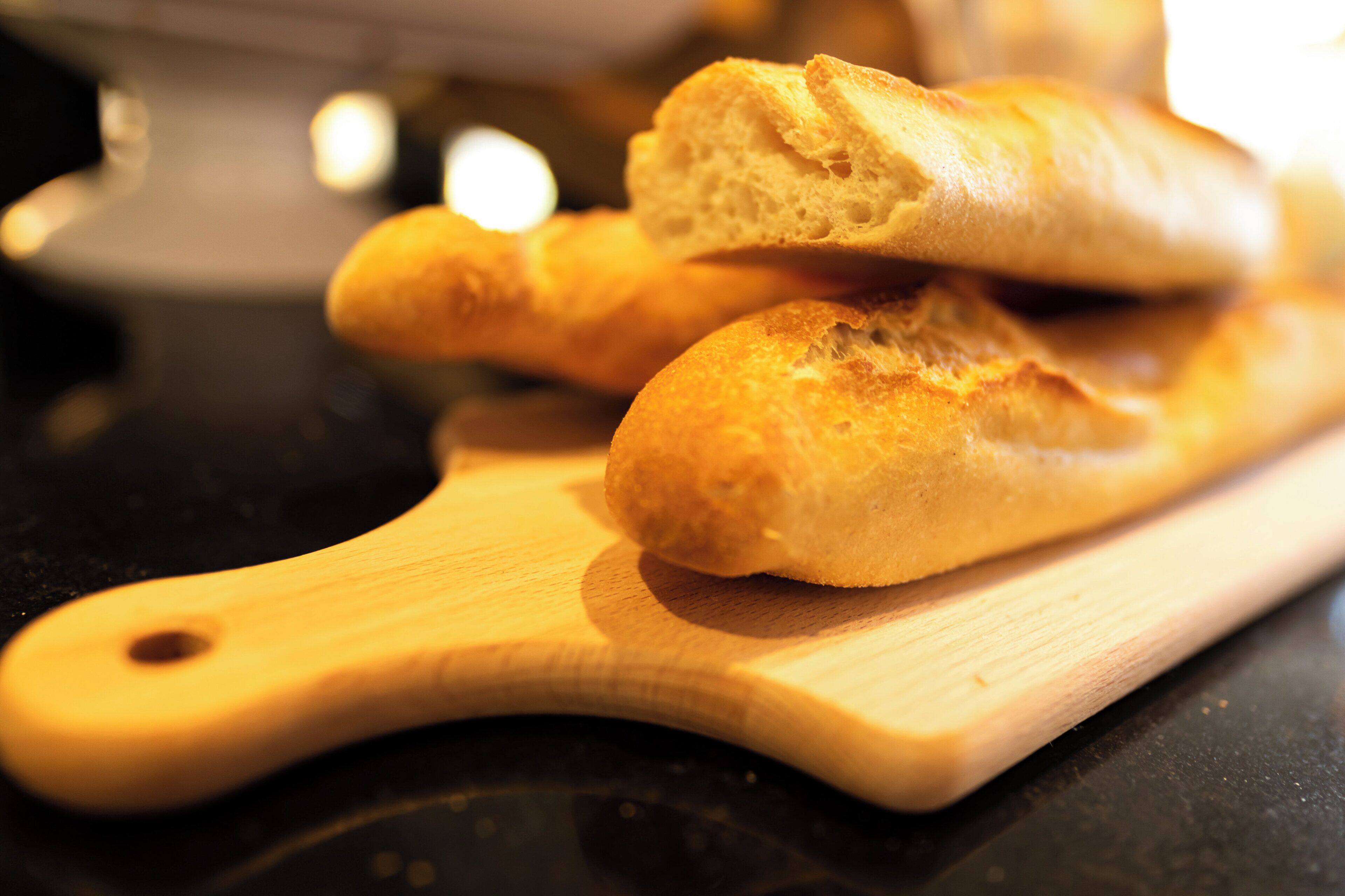 A wooden cutting board with two pieces of bread on it.