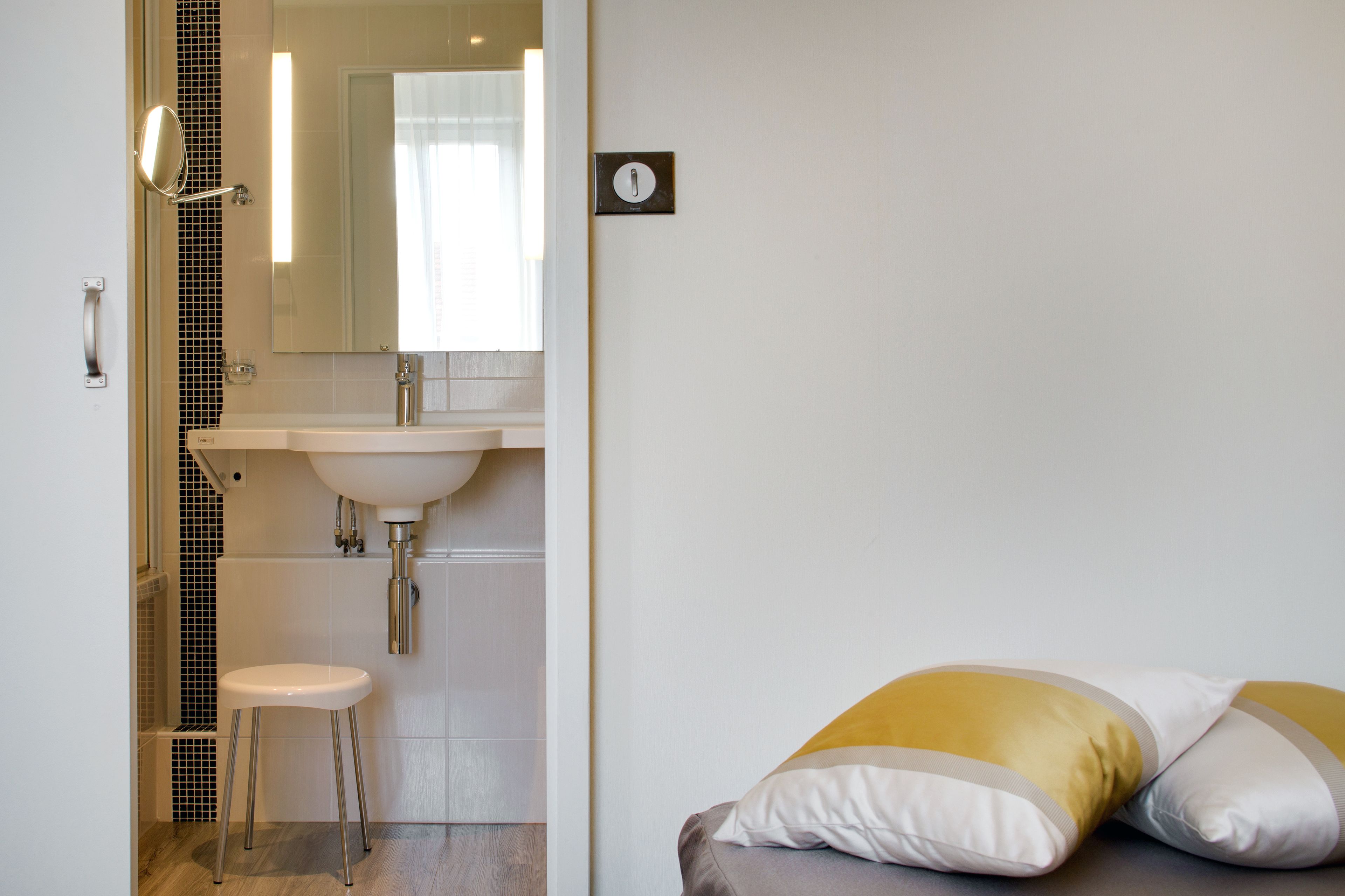 Une salle de bain avec un lavabo blanc, un miroir et des toilettes.
