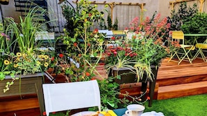 An outdoor dining table set with breakfast items, surrounded by lush greenery and a pergola. - HOTEL ARVERNA VICHY - ClT'HOTEL (Vichy)