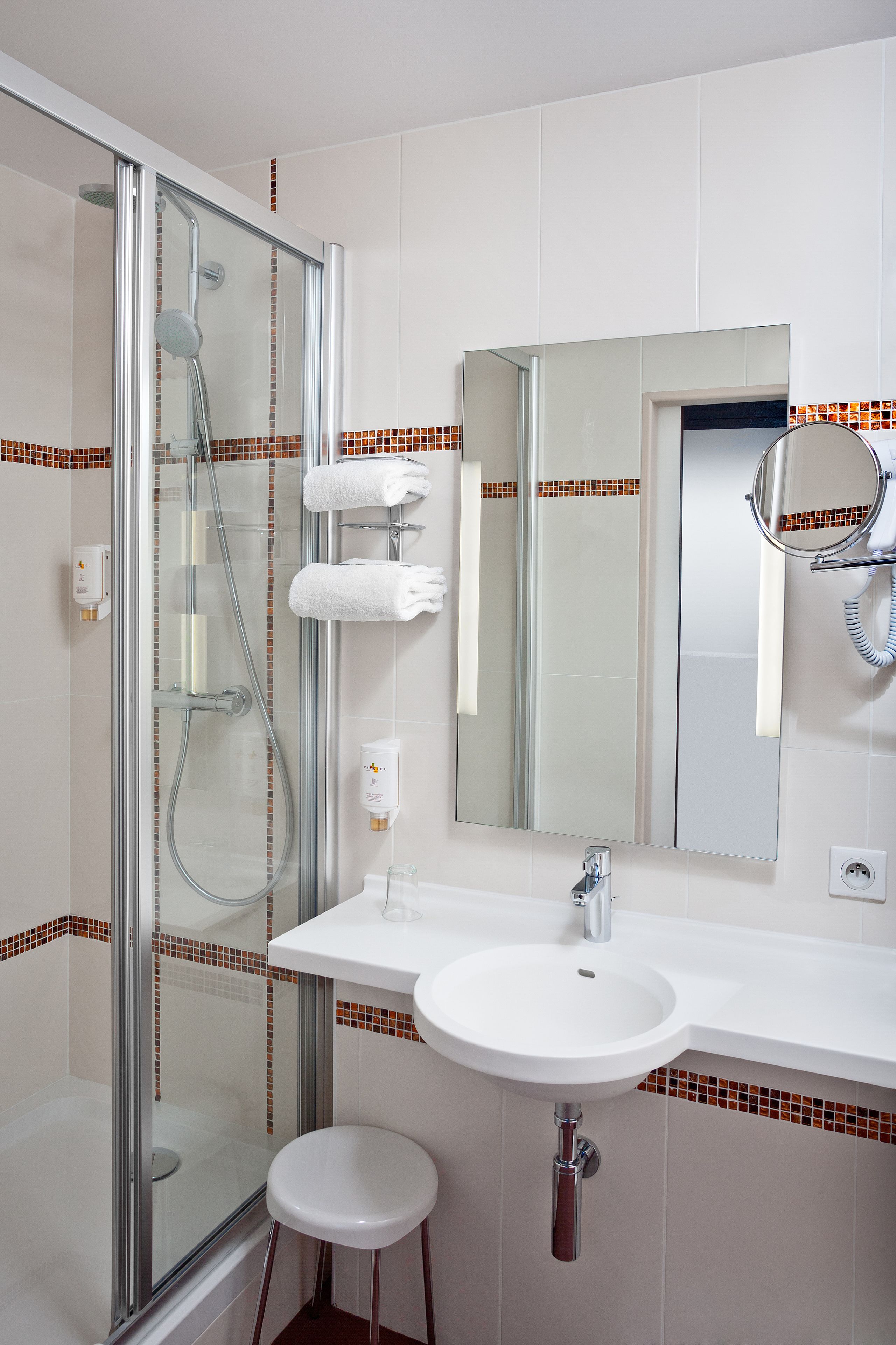 Un baño moderno con ducha envuelta en vidrio, un lavamanos blanco y un espejo.