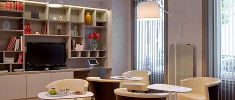 Un salon moderne doté d’un téléviseur à écran plat, de bibliothèques, d’une table basse et de sièges confortables.