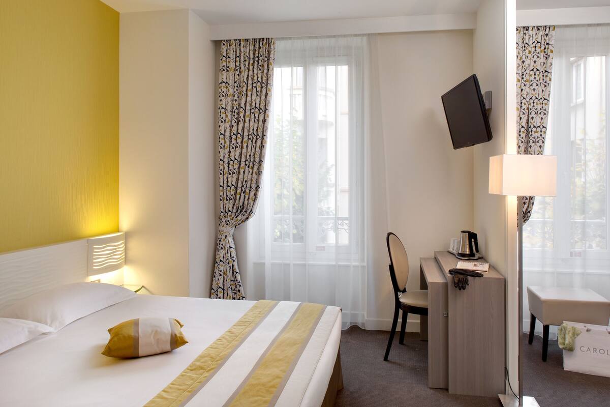 Una habitación de hotel con una cama, un escritorio, una silla, un televisor y una lámpara.