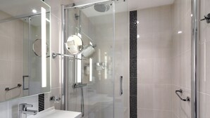 A modern bathroom with a glass-enclosed shower, a white sink, and a mirror with integrated lighting. - HOTEL ARVERNA VICHY - ClT'HOTEL (Vichy)