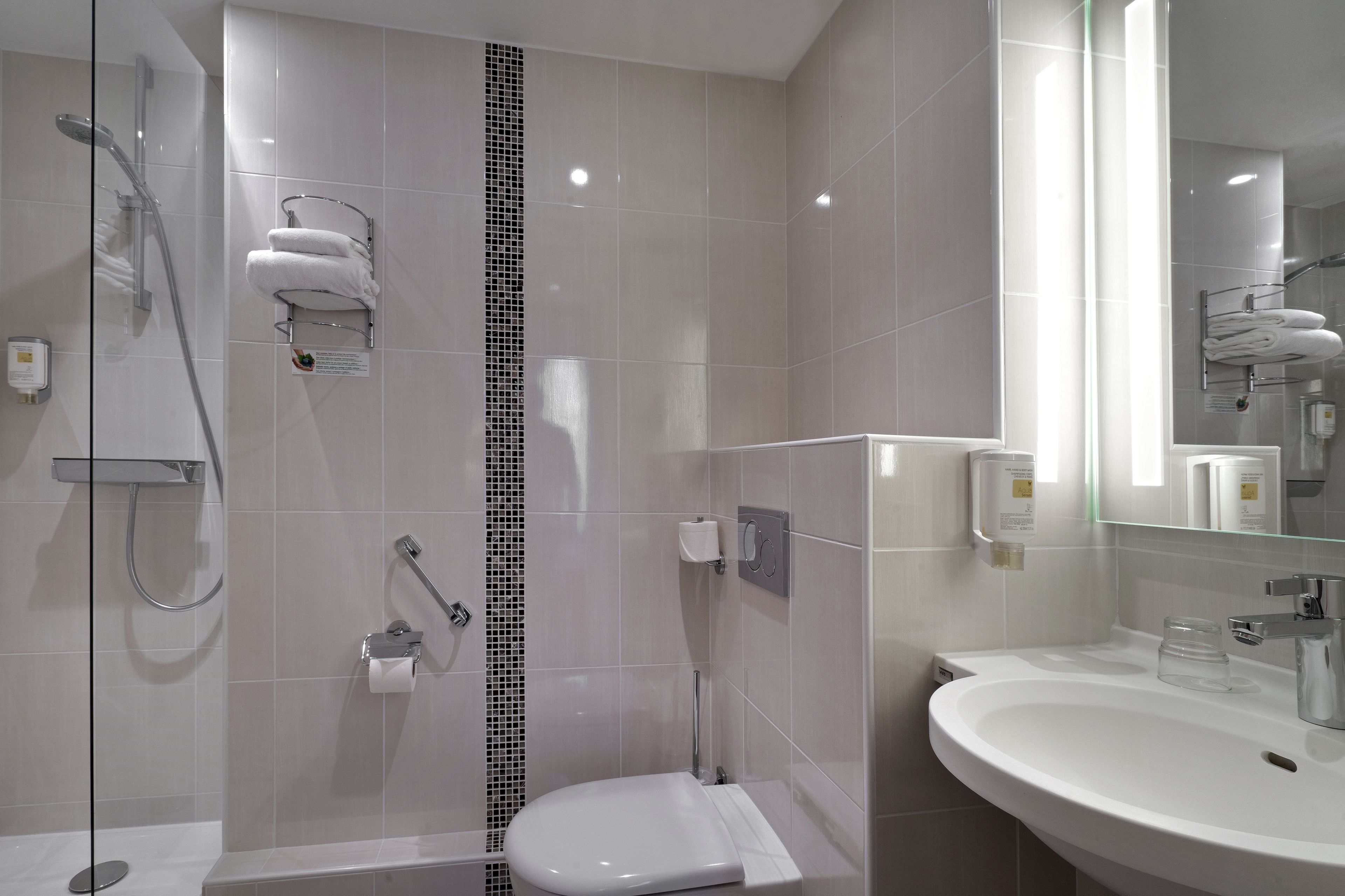 A modern bathroom with a glass-enclosed shower, a white sink, and a large mirror.