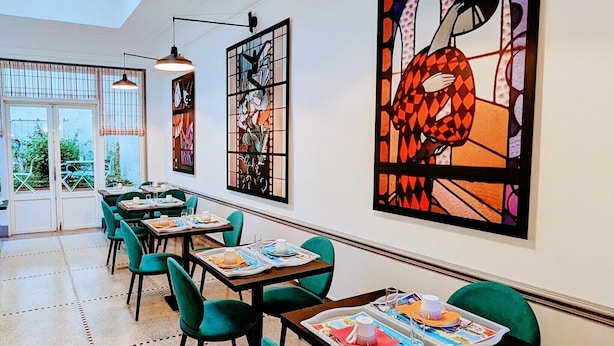 A dining area with tables and chairs, large windows, and artwork on the walls. - HOTEL ARVERNA VICHY - ClT'HOTEL (Vichy)