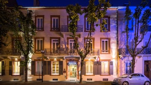 A hotel with a classic facade, multiple balconies, and a car parked in front. - HOTEL ARVERNA VICHY - ClT'HOTEL (Vichy)