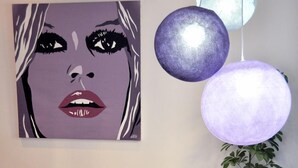 Un interior moderno con una zona de estar, una mesa con una revista, una planta en maceta y una obra de arte colgada en la pared.