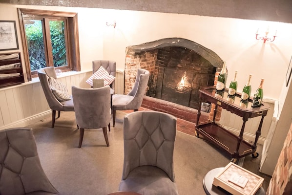 Una habitación acogedora con chimenea, asientos cómodos y una mesa con botellas.