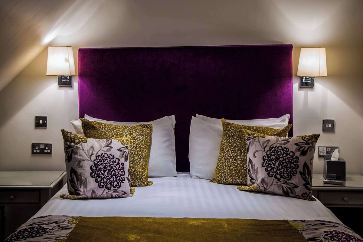 A hotel room with a large bed, two bedside lamps, and a nightstand with a tissue box.