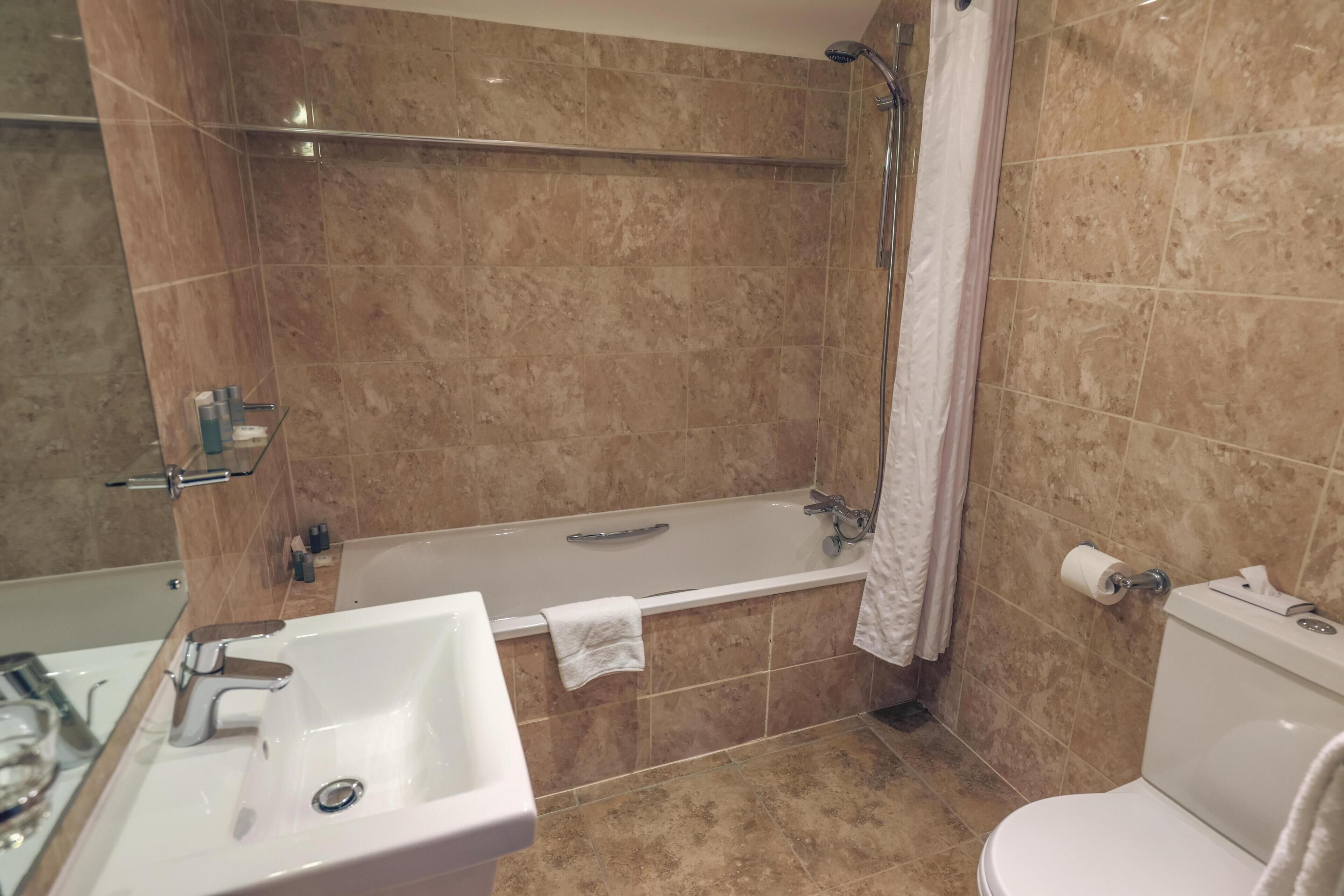 Un baño con bañera, inodoro, lavamanos y ducha.