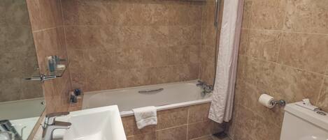 Un baño con bañera, inodoro, lavamanos y ducha.