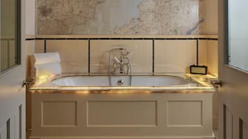A bathroom with a large bathtub, a map on the wall, and a tiled floor.