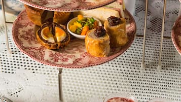 Um suporte escalonado para sobremesas com diversos doces e uma pequena tigela de doce.