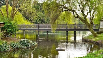 A tranquil riverside scene with a bridge, lush greenery, and a calm water body.