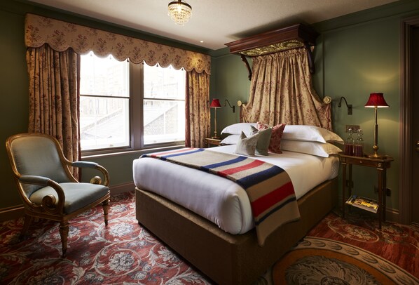 Une chambre à coucher de style traditionnel, avec un grand lit, une chaise et une fenêtre avec des rideaux.