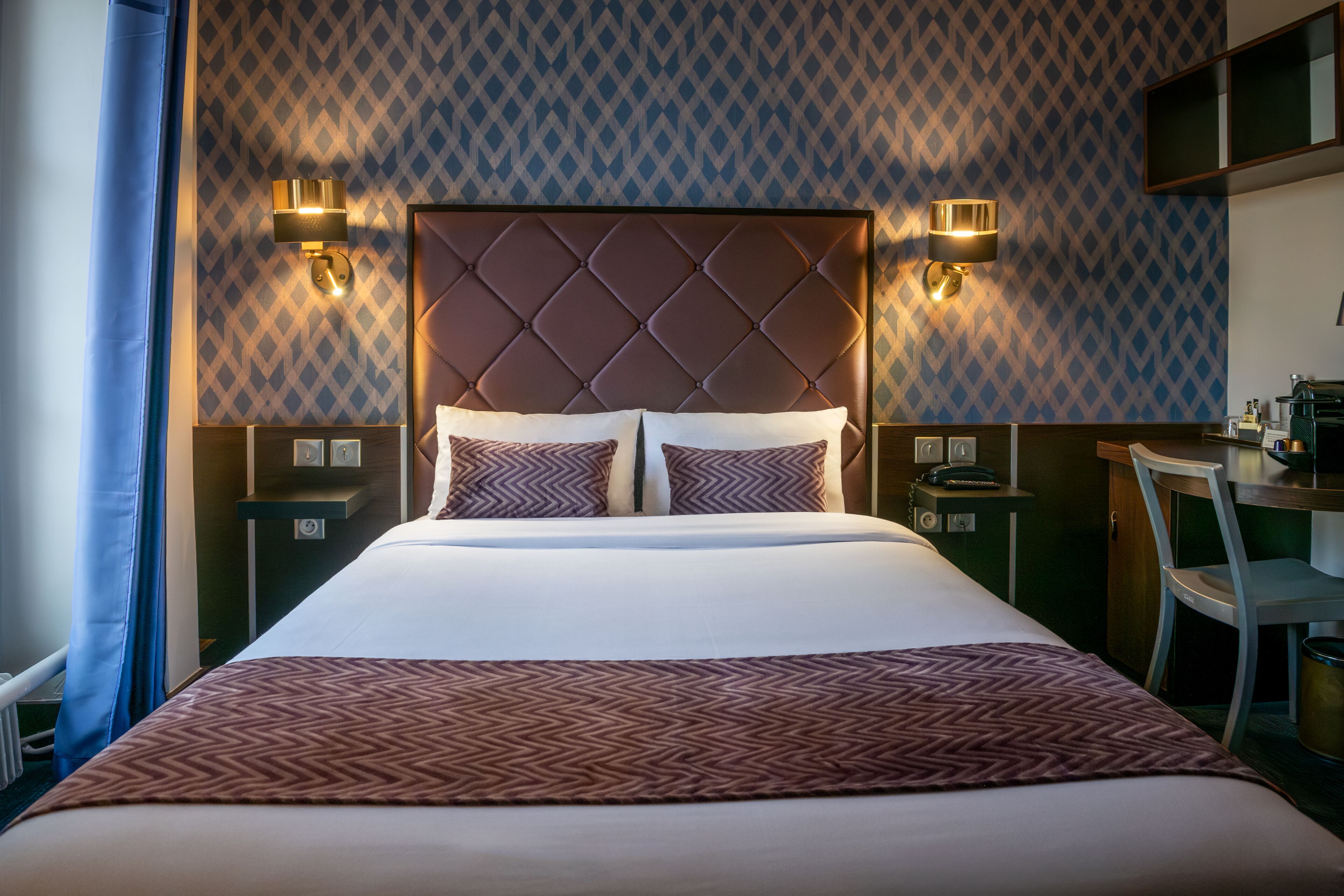 A hotel room with a large bed, two bedside tables, a desk, and a chair.