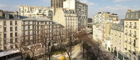Un paisaje urbano con un rascacielos, un hotel y un parque con una estatua.