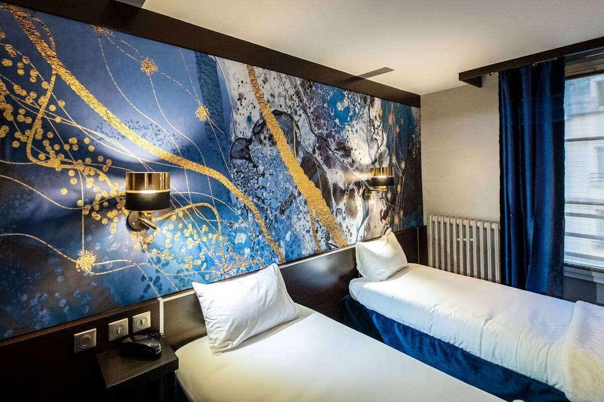 A hotel room with two beds, a large abstract mural on the wall, and a window with curtains.
