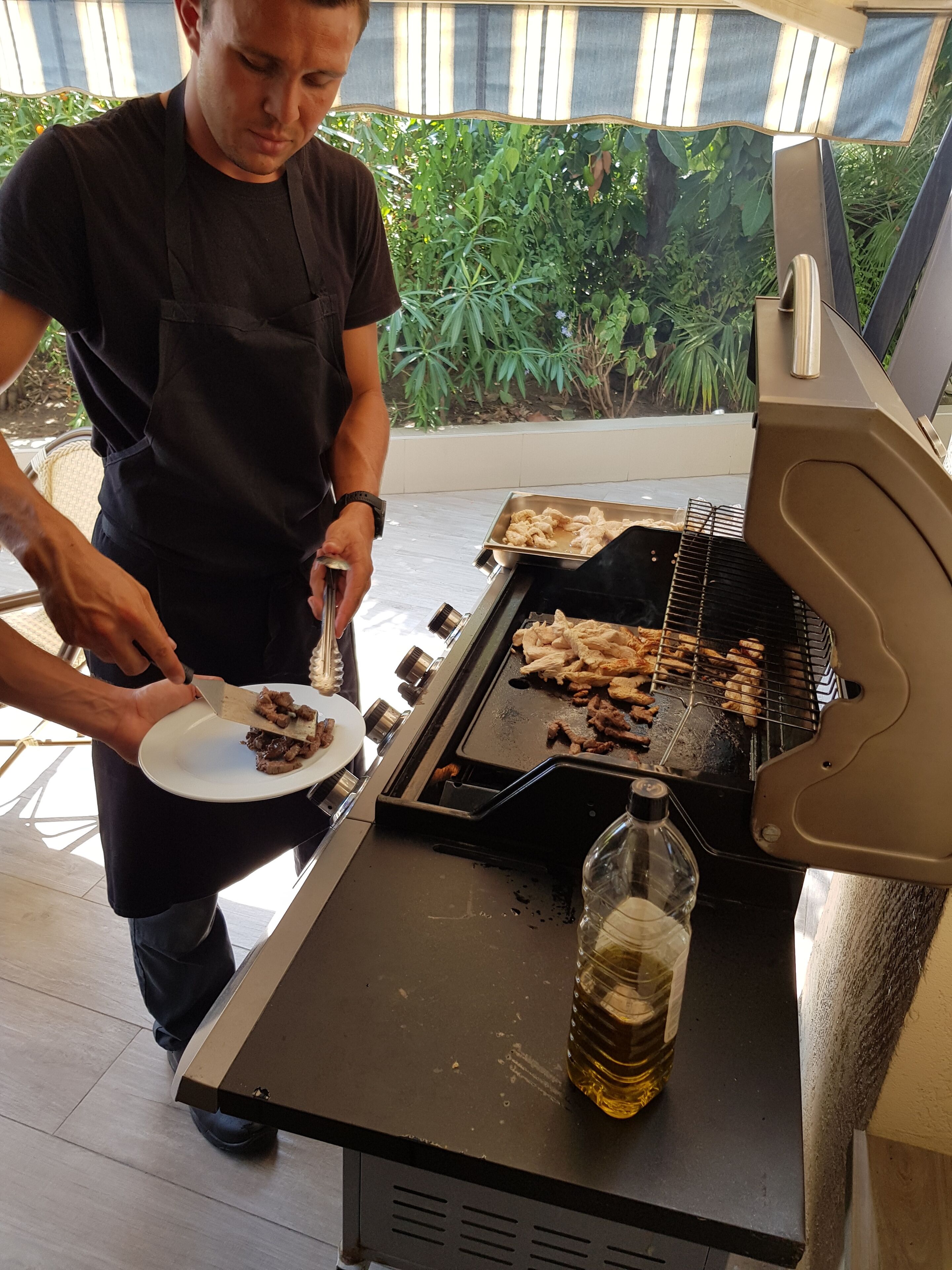 Eine Person grillt Fleisch auf einem Grill im Freien.
