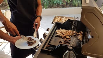 Eine Person grillt Fleisch auf einem Grill im Freien.