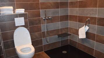 A bathroom with a toilet, a shower, and a towel rack.