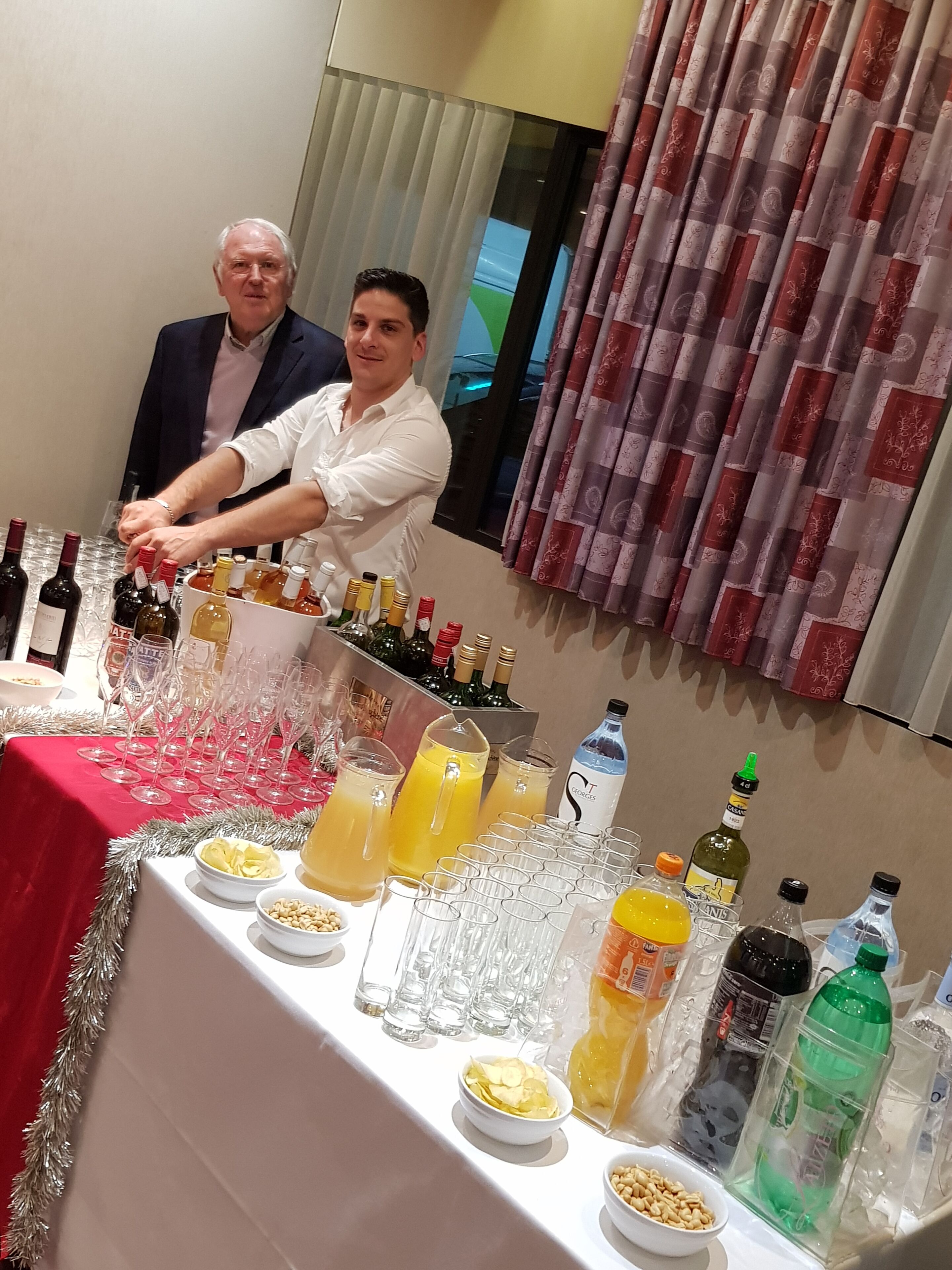 Una mesa dispuesta con diferentes botellas, vasos y aperitivos, probablemente para un evento social.